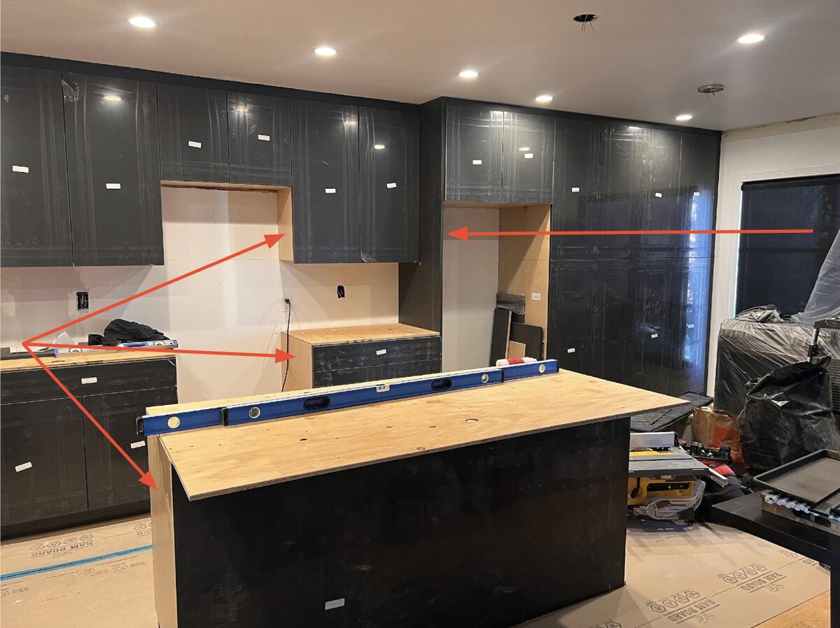 DodiHome cabinets staged on a jobsite with a level on the island and alignment lines marked on the wall cabinets